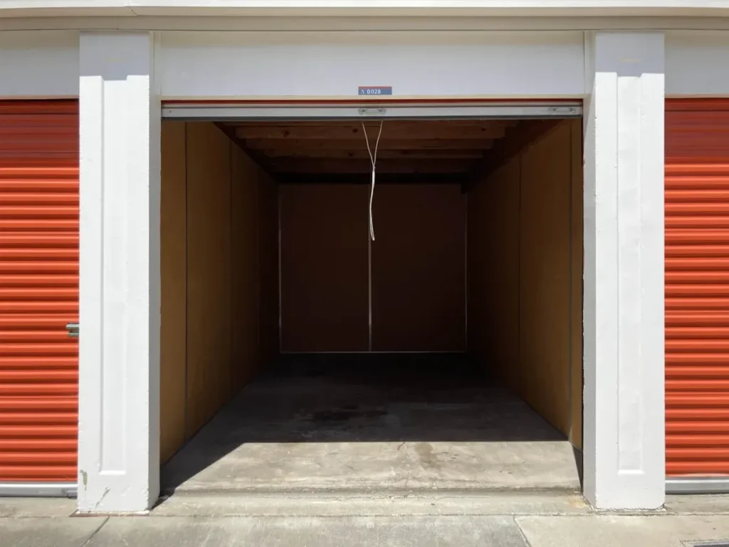 Mini bodega abierta y vacía, con puerta metálica enrollable y paredes de madera