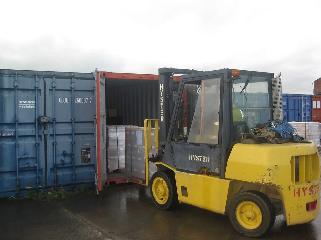 Montacargas metiendo tarimas con mercancía a una caja de carga con las puertas abiertas