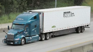 Caja refrigerada blanca de 53 pies enganchada a un tractocamión en carretera